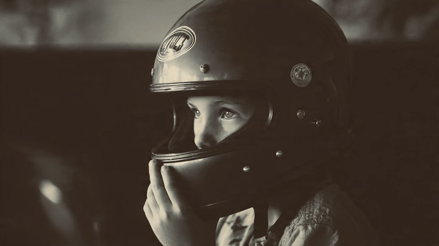 Little boy holding a motorcycle helmet, standing confidently in front of a class for a school project.