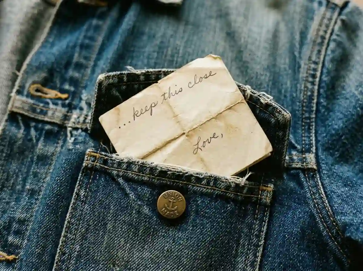 A folded handwritten note tucked into the pocket of a denim jacket