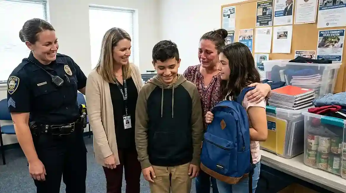 Community members gathered in the police station smiling at Finn
