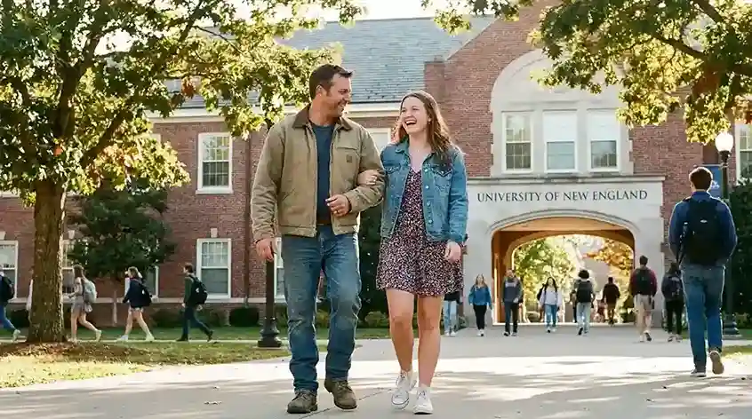 Father and daughter walking arm in arm onto a university campus