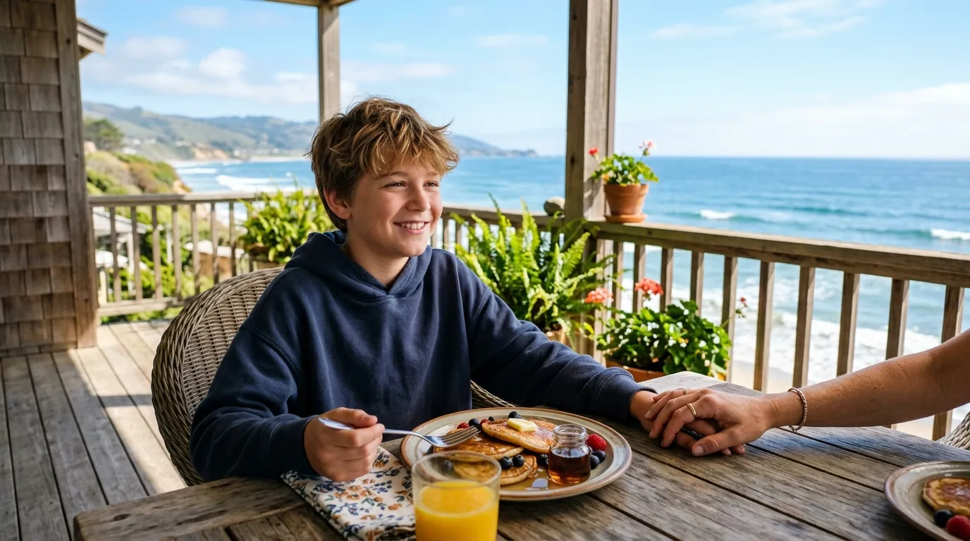 A mother and son sharing a peaceful breakfast on a porch overlooking the ocean