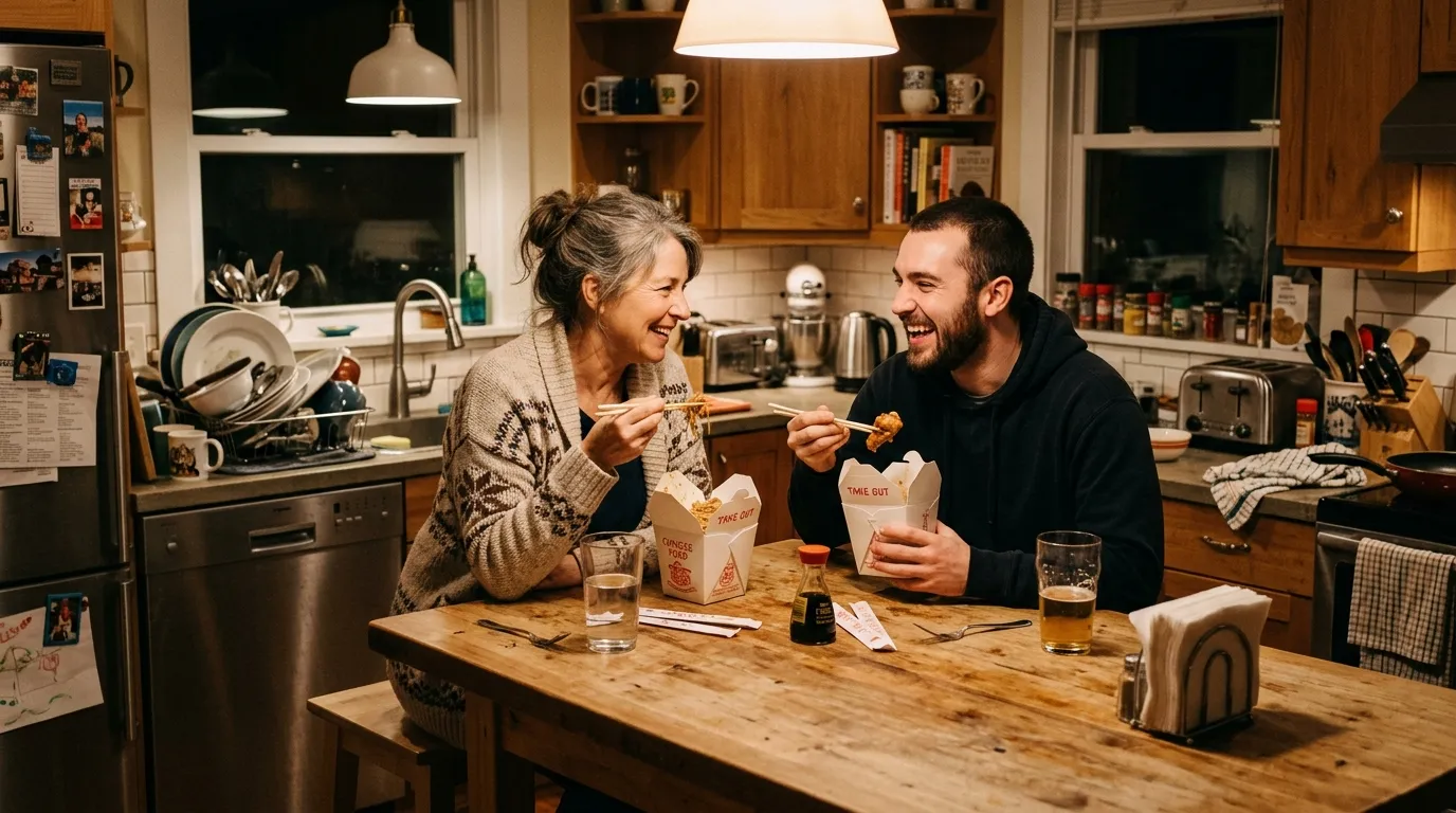 A mother and son laughing and eating Chinese takeout in a messy kitchen